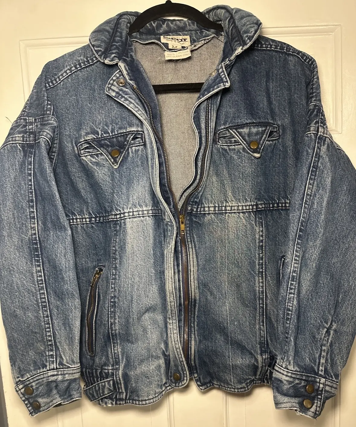 Faded blue denim jacket with flap chest pockets, zipper and snap cuffs