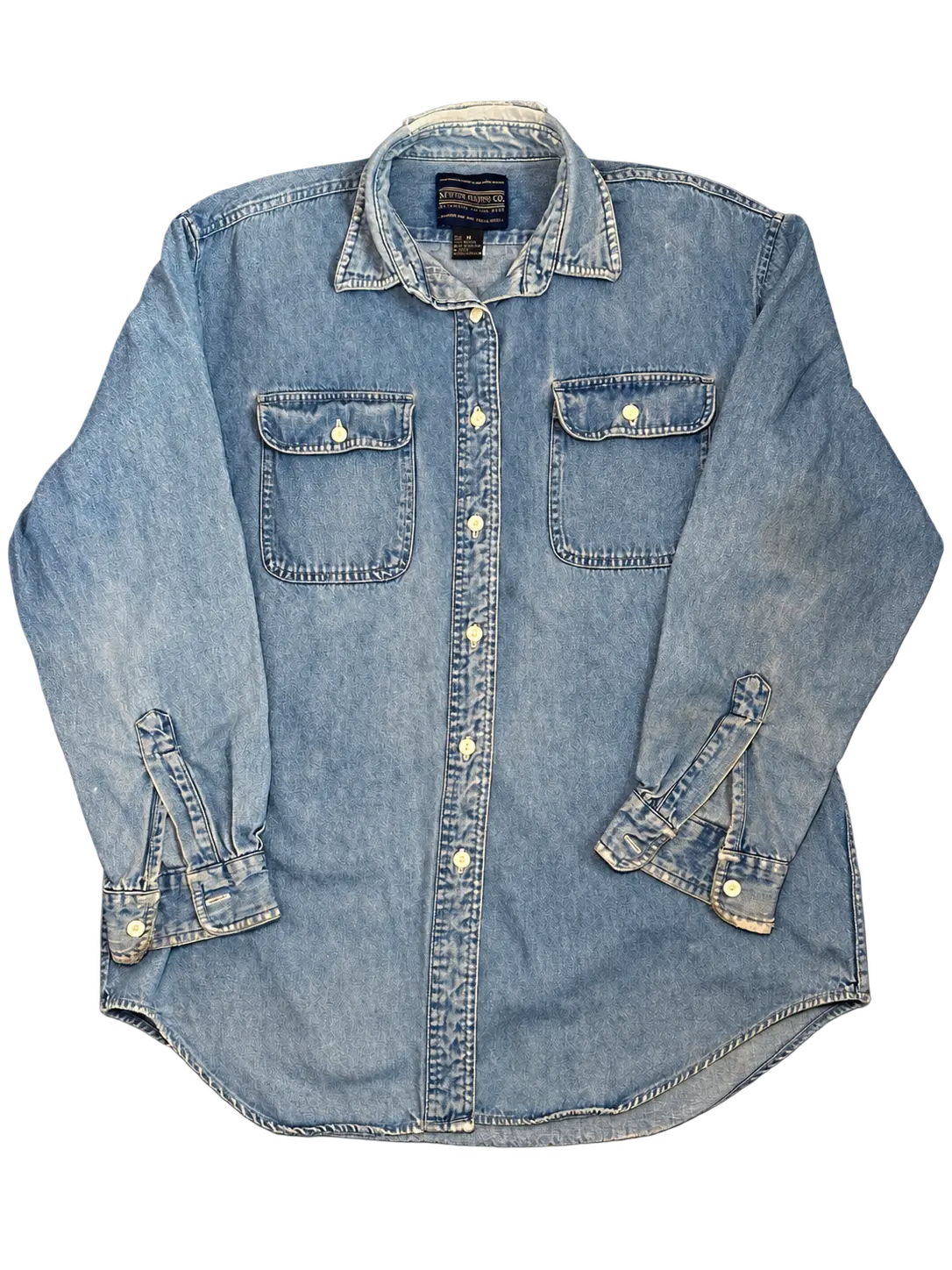 Background-free cutout of a light-wash Newton Trading Co. denim button-up shirt