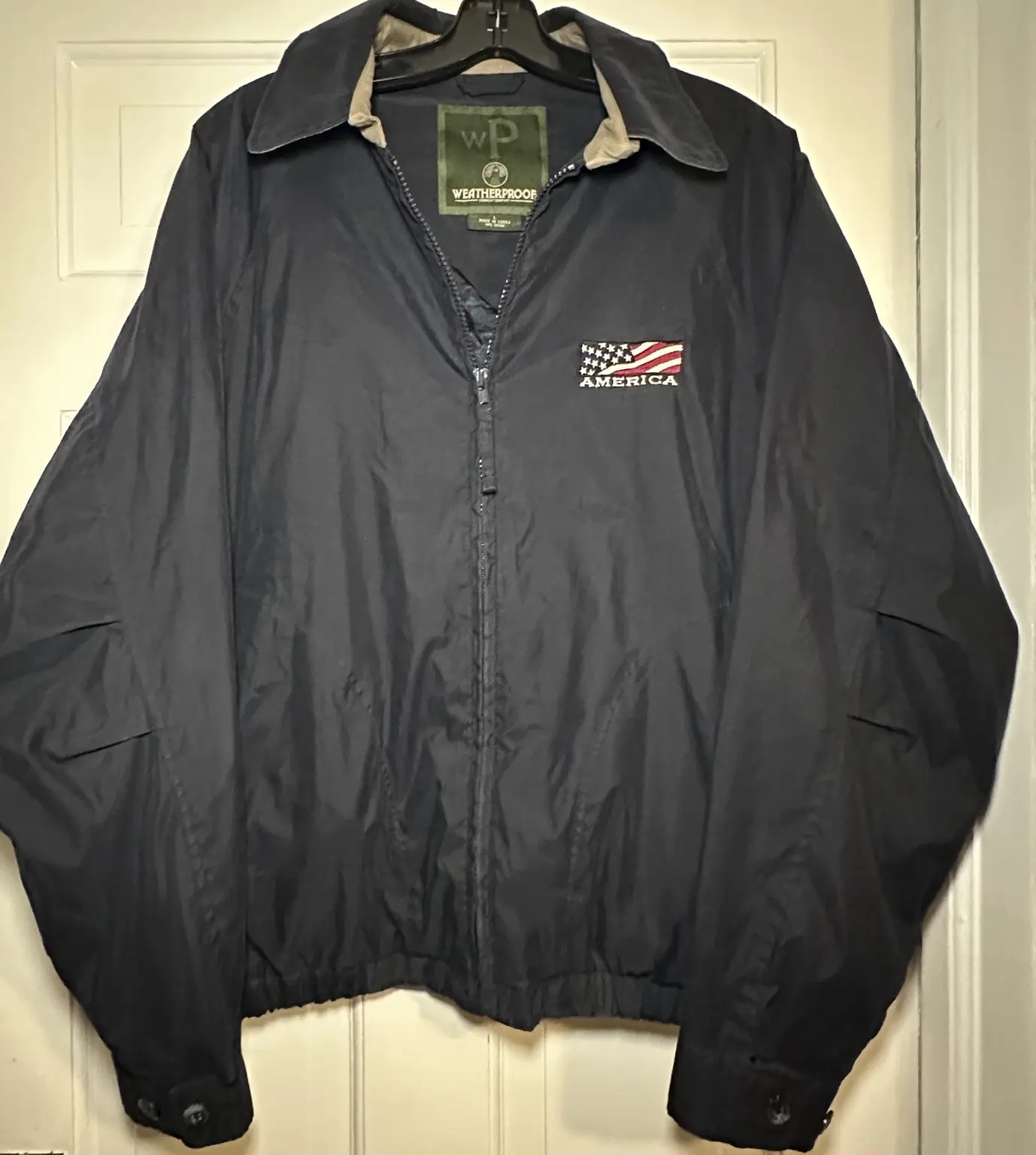 Navy Weatherproof zip-up jacket with embroidered American flag and America lettering on chest